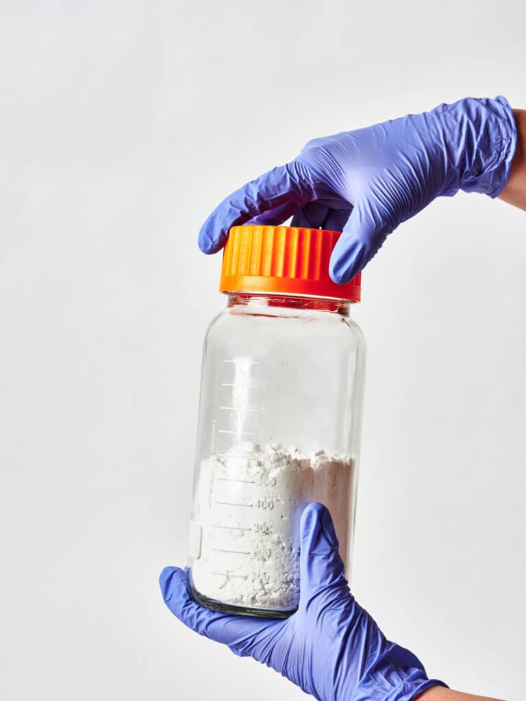 bulk cbd isolate in pyrex jar held by lab technician 